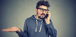 Man talking on the phone, looking annoyed at nuisance phone call