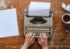 Writing retreats Hands typing on a typewriter, next to a piece of paper and cup of coffee
