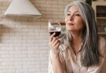A woman with a glass of red wine at home in the kitchen