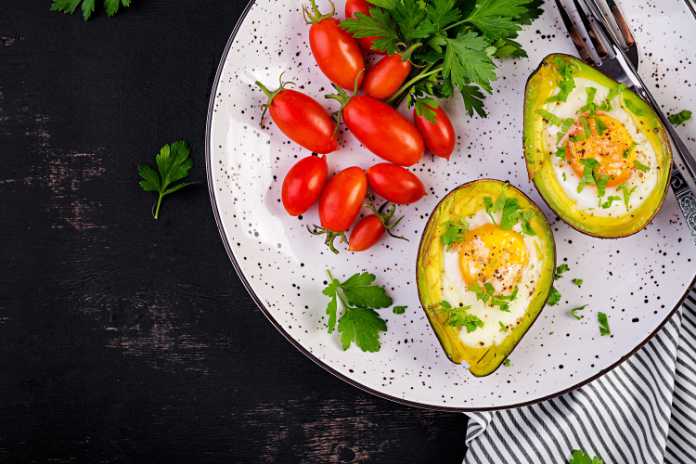 Photo of baked eggs in avocados with tomatoes.
