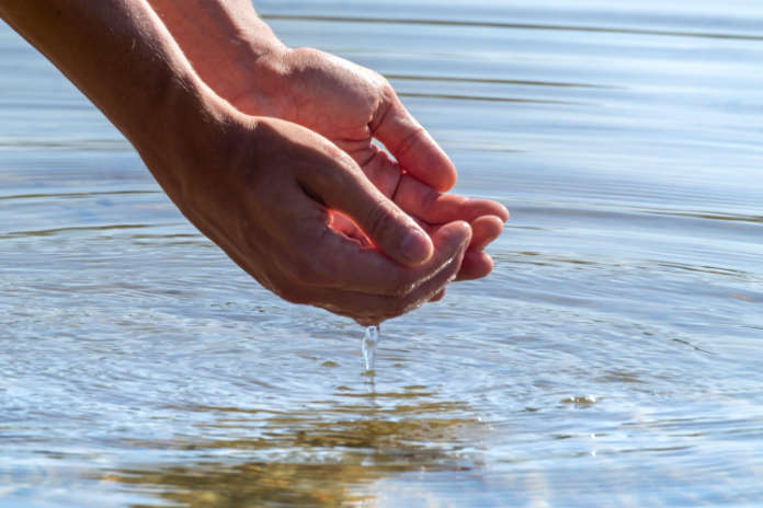 Close-up of hands holding water with reflection. 