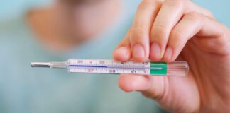Closeup of a man holding a thermometer for measuring body temperature degrees Celsius at 38,5 background.