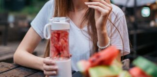 Woman eating with a portable mini blender with fruit