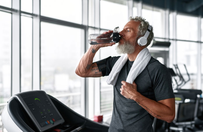 Mature athletic man stays hydrated when exercising