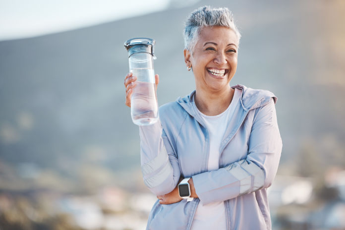Keeping hydrated is essential with mature woman drinking water before a workout