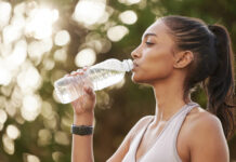 The importance of staying hydrated when exercising – Shot of a sporty young woman drinking water while exercising